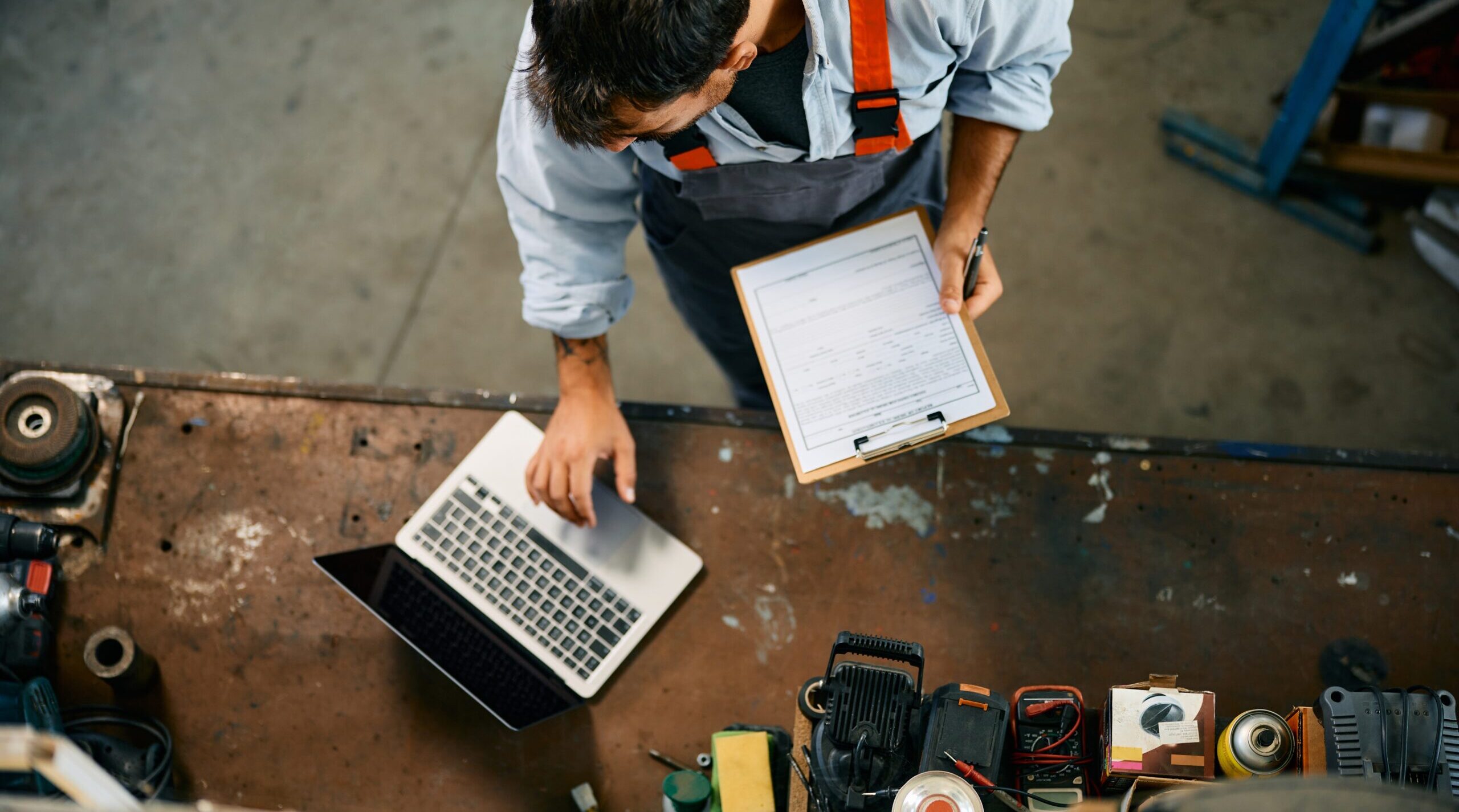 Direct bovenaanzicht van een monteur die een laptop gebruikt tijdens het werken