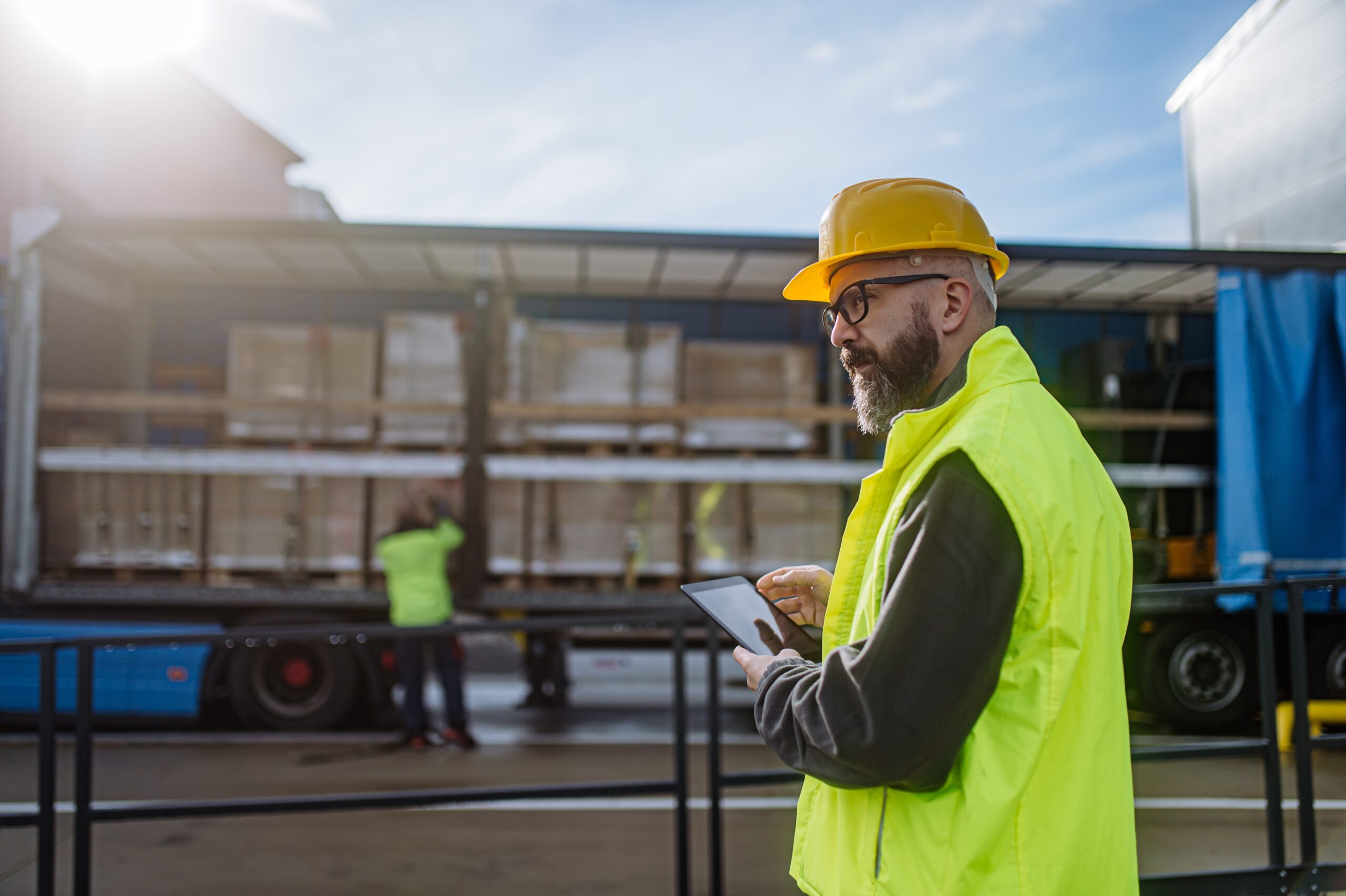 Magazijnmanager houdt toezicht op het lossen van een vrachtwagen met een tablet in zijn handen